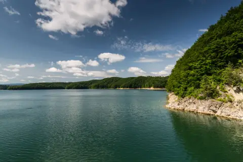 Spokojne jezioro otoczone zielonymi wzgórzami, idealne miejsce na sporty wodne.