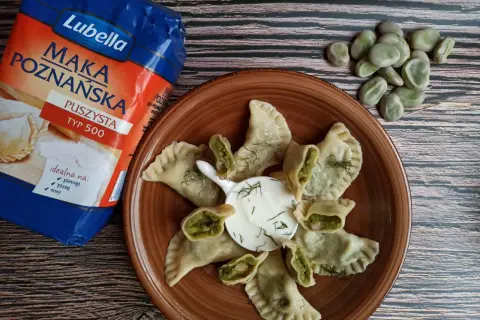 Pyszne pierogi z bobem, podane z kwaśną śmietaną i koperkiem, obok mąki Lubella.