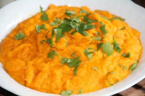 Purée de carotte onctueuse, garnie de feuilles de coriandre fraîche. Un délice orangé et savoureux.