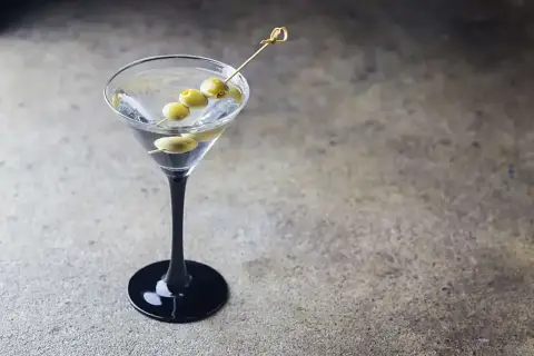 Elegancki dirty martini z trzema oliwkami na wykałaczce, gotowy do degustacji.
