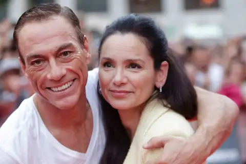 Jean-Claude Van Damme z żoną, uśmiechnięci, w tłumie.