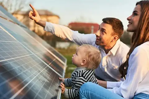 Rodzina podziwia panele fotowoltaiczne w Polsce. Ojciec pokazuje dziecku, jak działa czysta energia.