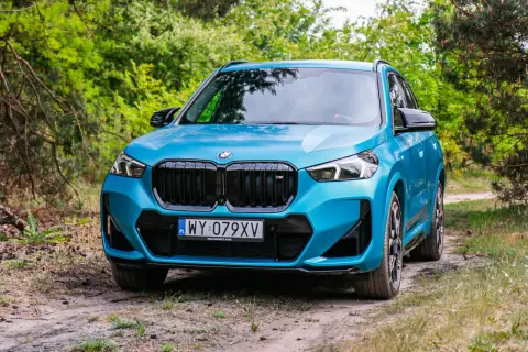 Niebieskie BMW X1 na leśnej drodze. Sprawdź jego kompaktowe bmw x1 wymiary, idealne do miasta i poza nim.