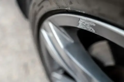 Zbliżenie na uszkodzoną, porysowaną felgę aluminiową samochodu.