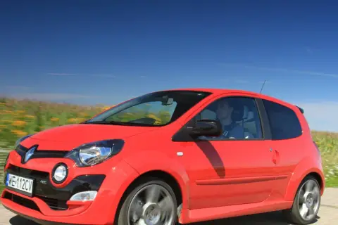 Czerwone Twingo RS pędzi przez kwitnące pola pod błękitnym niebem.