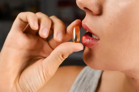 Mujer a punto de tomar una cápsula de colágeno. ¿Cuál es la mejor hora para tomar colágeno?