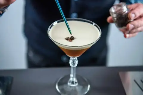 Barman dodaje ziarna kawy do drinka z pianką, przypominającego Espresso Martini. To właśnie kahlua co to za likier?