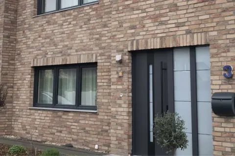Nowoczesne drzwi zewnętrzne i okno na ceglanej ścianie domu.