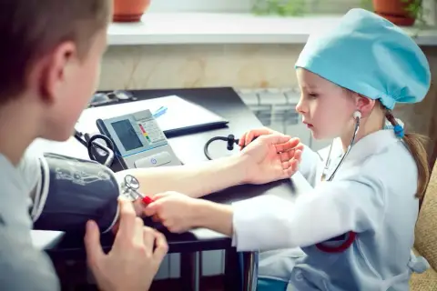 Dziecko w stroju lekarza mierzy ciśnienie. Czy tauryna podnosi ciśnienie? To pytanie, na które odpowiedzi szukają mali medycy.