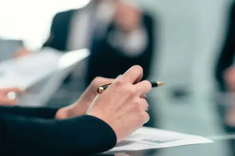 Dłonie trzymające długopis nad dokumentami podczas spotkania w alektum capital ii ag.