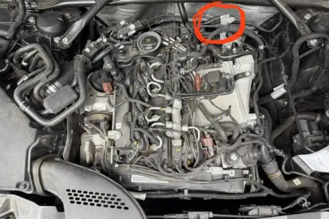 Motorraum eines Mercedes mit rotem Kreis um einen Sensor.