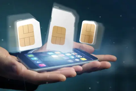 Dłoń trzyma smartfon, nad którym unoszą się karty SIM różnych rozmiarów, symbolizujące aktywację karty SIM i wybór odpowiedniego formatu.