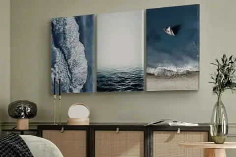 Un marco triptico con vistas al mar: olas rompiendo en la orilla, aguas tranquilas y un velero solitario.