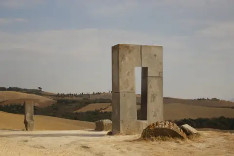 Scultura moderna in cemento nel paesaggio collinare toscano, sito transitorio Asciano.