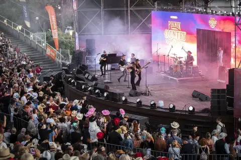 Na scenie podczas Piknik Country Mrągowo gra zespół, a publiczność w kapeluszach bawi się w rytm muzyki.
