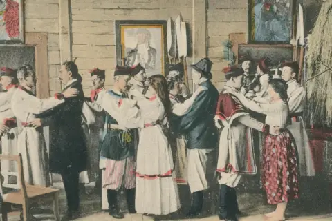 Scena weselna w stylu Wyspiańskiego. Ludzie w strojach ludowych tańczą, a na ścianach wiszą obrazy.