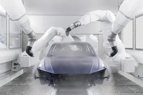 Robots pintan un coche entero en una cabina de pintura.