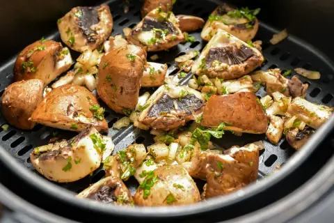 Pyszne pieczarki z airfryer, przyprawione i posypane natką pietruszki, gotowe do podania.