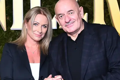 Marcin Daniec z żoną na tle zielonej ściany z ozdobnymi literami.