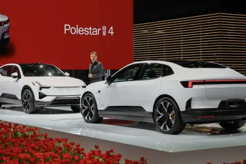 Dwa białe samochody Polestar 4 na scenie z czerwonym tłem i tulipanami.