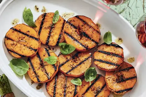 Tranches de courge au barbecue, grillées et assaisonnées, garnies de feuilles de basilic frais. Un délice estival !