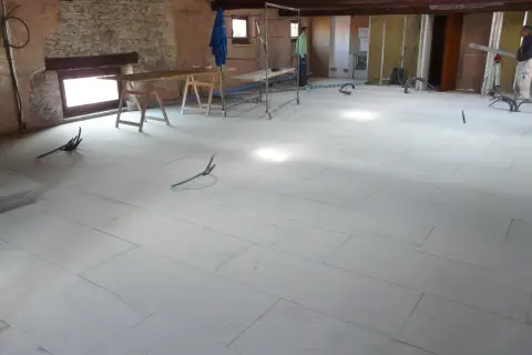 Pannelli per insonorizzare il pavimento in fase di posa, con tubi e attrezzature da cantiere.