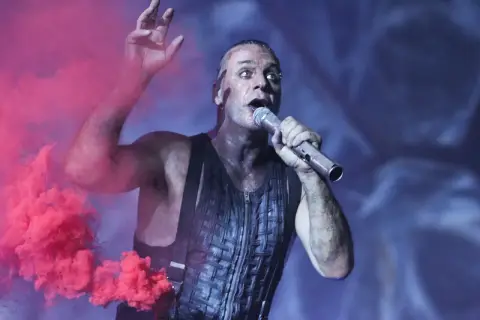 Till Lindemann śpiewa "Sonne" Rammstein, otoczony różowym dymem. Tekst po polsku tej piosenki jest równie intensywny.