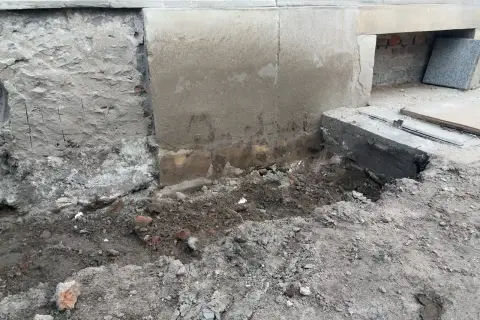 Prace przy podbijaniu fundamentów. Widoczny wykop i fragmenty muru.