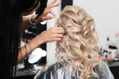 Fryzjer po hiszpańsku, czyli "peluquero", tworzy piękną fryzurę ślubną z blond loków.