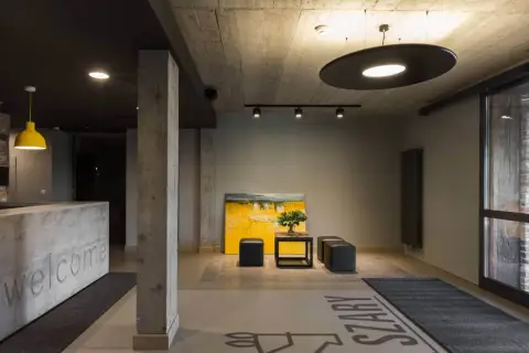 Nowoczesne wnętrze z betonowymi elementami i obrazem. Na podłodze widoczne są eleganckie podłogi epoksydowe z napisem "SZARY".
