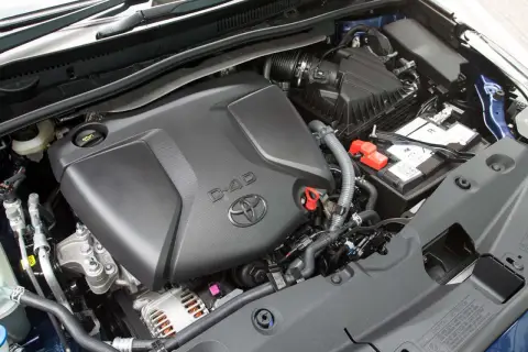 Silnik D-4D w Toyota Avensis T27. Widoczny jest czarny plastikowy dekiel silnika z logo Toyoty i napisem D-4D, akumulator oraz elementy układu dolotowego.