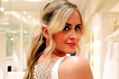 Valentina Ferragni sonríe con un vestido blanco de tirantes y detalles de perlas, en una tienda de novias.