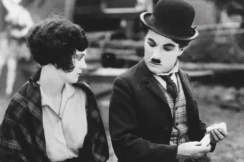 Charlie Chaplin och en kvinna i en klassisk chaplin film. Han ser bekymrad ut medan hon betraktar honom.