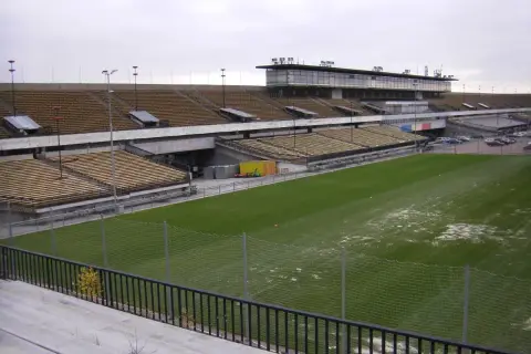 Pusta trybuna stadionu, największy stadion w Czechach, z zieloną murawą i ogrodzeniem.