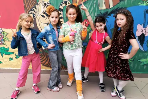 Pięć dziewczynek w kolorowych strojach, gotowych na imprezę w stylu disco.