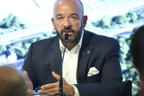 Jacek Sutryk z partnerem podczas konferencji prasowej. Mężczyzna w garniturze przemawia do mikrofonu.