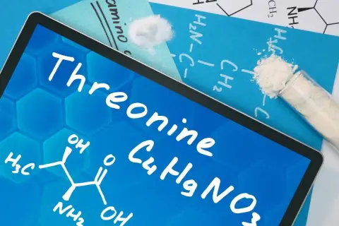 Tablet z napisem "Threonine" i wzorem chemicznym. Obok proszek w probówce i na kartce.