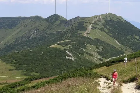 Widok na góry z turystką na szlaku. W oddali widać szczyt Chleb, Hromové i sedlo za Hromovým.