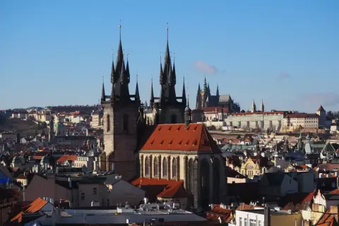 Gotycka wieża w Pradze góruje nad miastem, a w tle widać zamek.