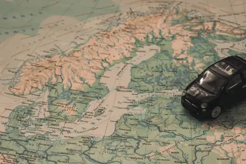 Czarny Fiat 500 na mapie Europy, planujący podróż na Mikołajki do Olsztyna.