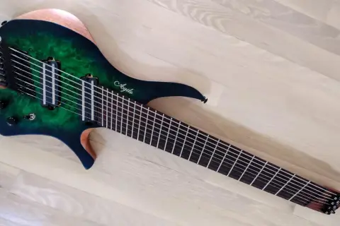 Guitare électrique Agile multiscale vert émeraude, avec 9 cordes et un manche fin, posée sur un parquet clair.