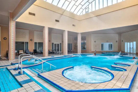Wnętrze basenu z hydromasażem w Mahdia Palace. Woda jest turkusowa, a wokół basenu znajdują się leżaki.