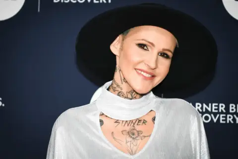 Agnieszka Chylińska w białej bluzce i czarnym kapeluszu, z widocznymi tatuażami na szyi i klatce piersiowej.