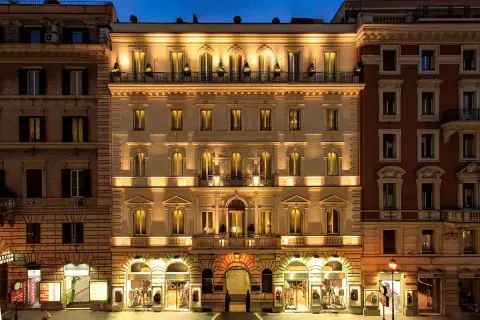 Edificio illuminato di notte, con negozi al piano terra, nel quartiere Esquilino a Roma.