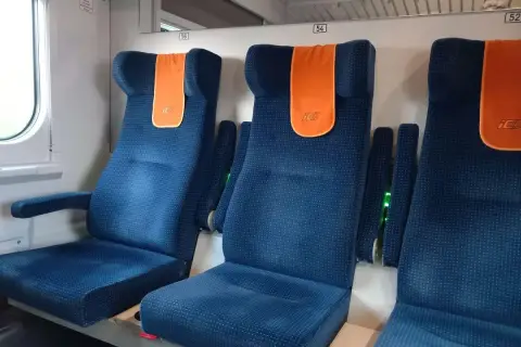 Komfortowe miejsca w pociągu Intercity. Siedzenia są niebieskie, z pomarańczowymi zagłówkami.