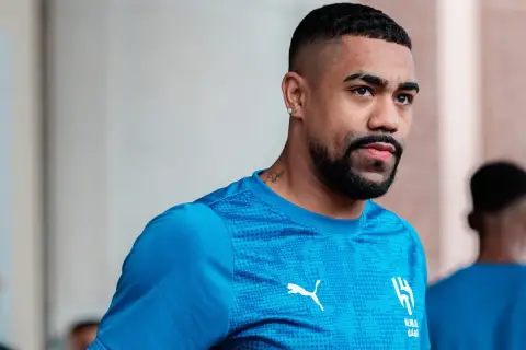 Piłkarz Malcom w niebieskiej koszulce z logo Al-Hilal i Pumy, z tatuażem na szyi.