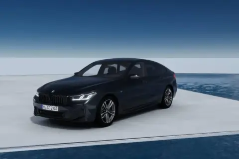 Eleganckie bmw g32 w ciemnym kolorze prezentuje się na platformie nad wodą, z błękitnym niebem w tle.