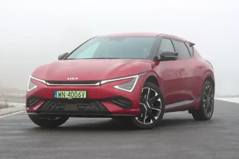 Czerwone Kia EV6 GT na mokrej drodze, w tle mgła.