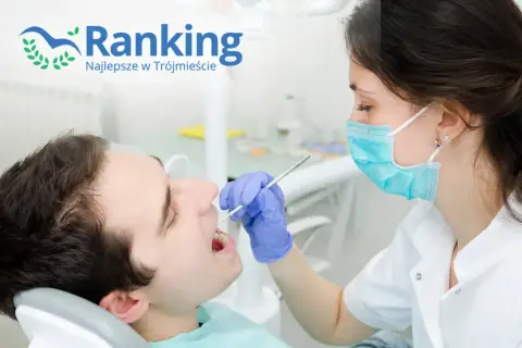 Dentystka w masce bada zęby pacjenta narzędziem stomatologicznym.