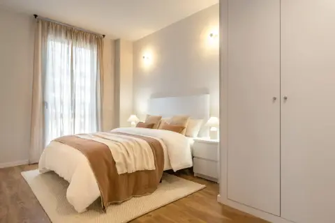 Dormitorio acogedor con cama vestida, cortinas vaporosas y apliques de pared que crean una atmósfera de luz cálida, neutra y fría.
